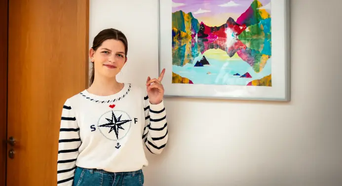 Eine Schülerin zeigt auf ein Bild an der Wand.