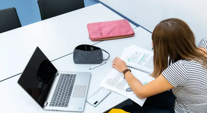 Studierende lernt mit Laptop und Unterlagen.
