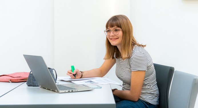 Eine Studierende sitzt am Laptop