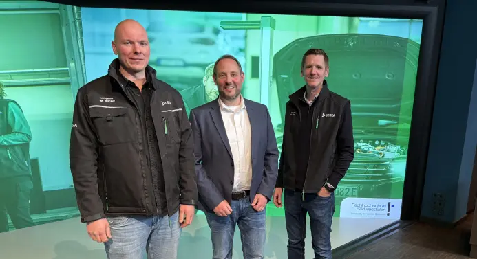 Drei Männer (Markus Bücker, Prof. Dr. Mark Fiolka und Oliver Nölle) stehen vor einer großen Leinwand, auf die eine Präsentation projeziert wird.