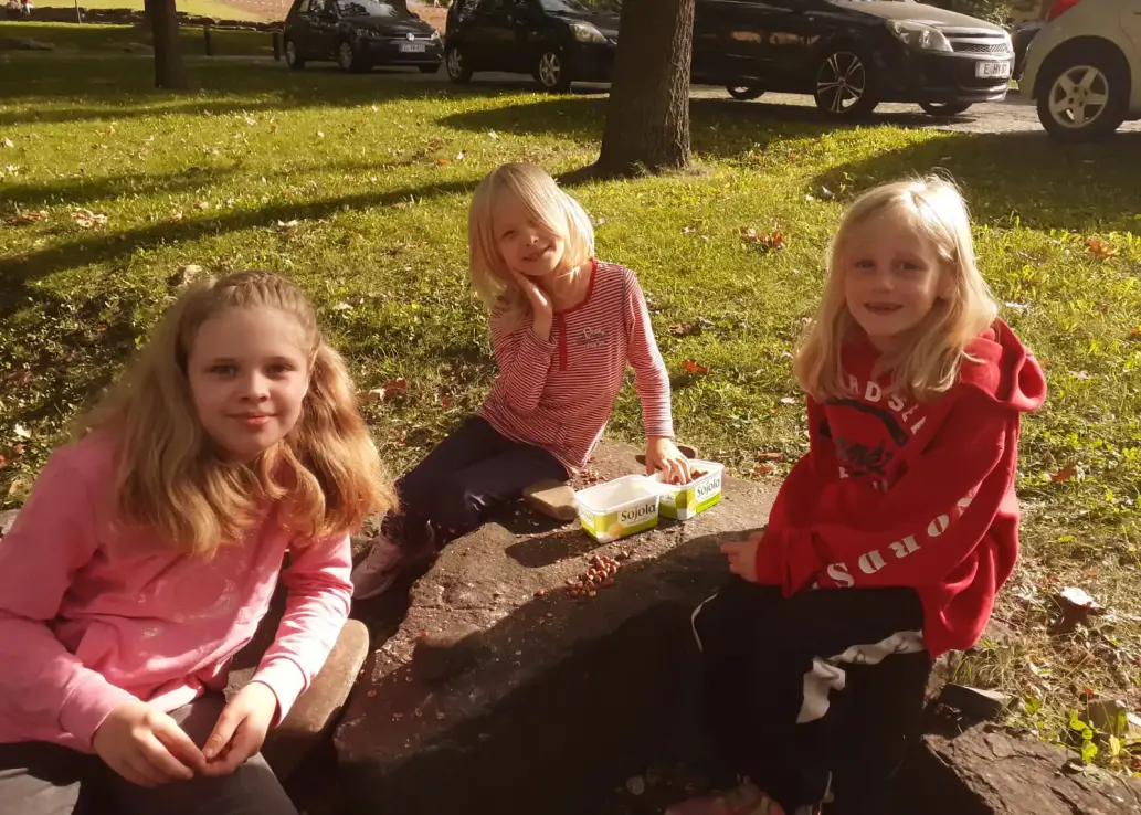 Kinder Sitzen auf einer Stein und knacken Nüsse